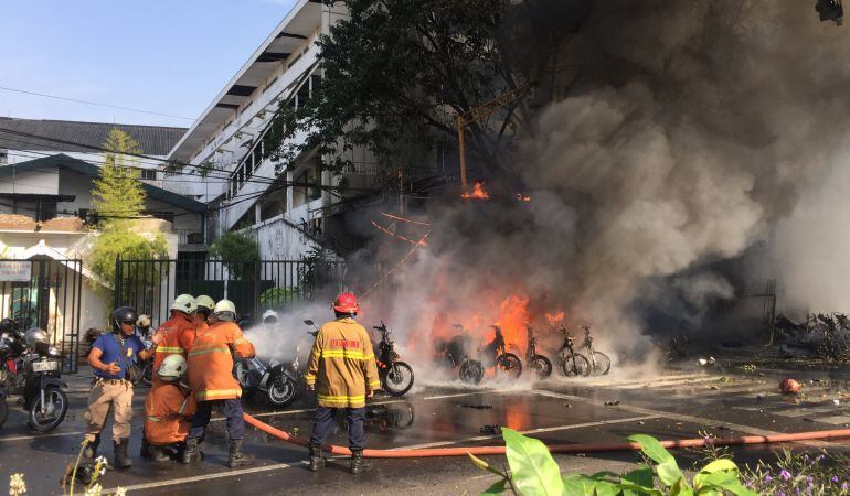 Los bomberos apagan un fuego en la puerta de una iglesia de Indonesia.