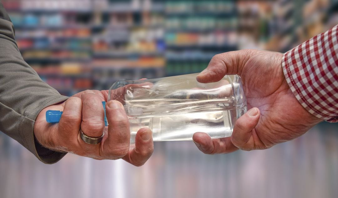 Dos personas sujetan una botella de gel hidroalcohólico