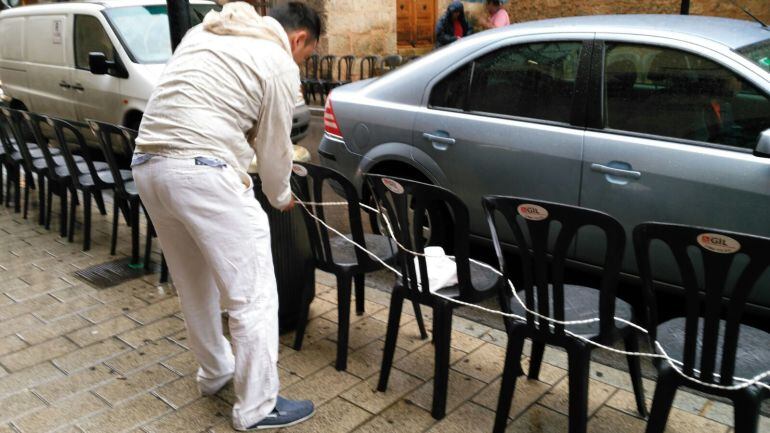 Un hombre coloca una cuerda para reservar varias sillas para la cabalgata.