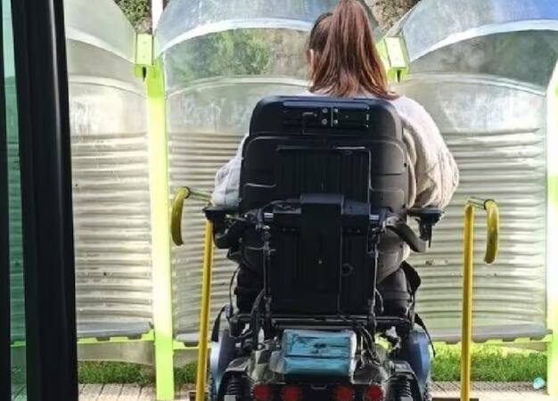 Una dona amb discapacitat en una parada de transport públic