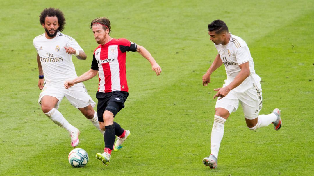 Muniain conduce un balón ante Marcelo y Casemiro en el partido disputado este domingo en San Mamés