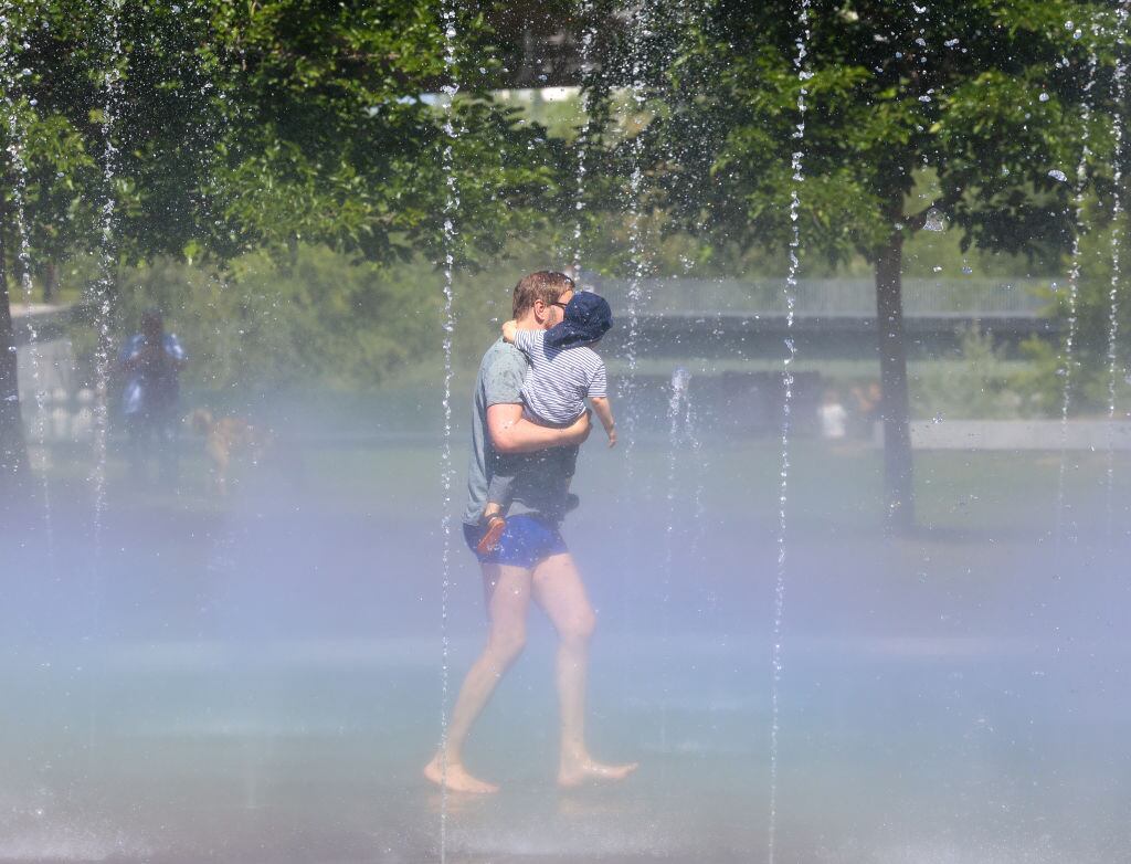 Un hombre se refresca con su hijo en los chorros de Madrid Río.