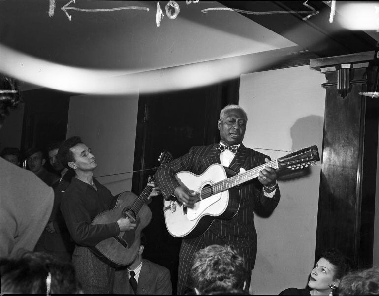 Woody Guthrie y Lead Belly en 1940 durante una actuación en un apartamento de Chicago para recaudar fondos para el Comité de las Artes y las Ciencias.