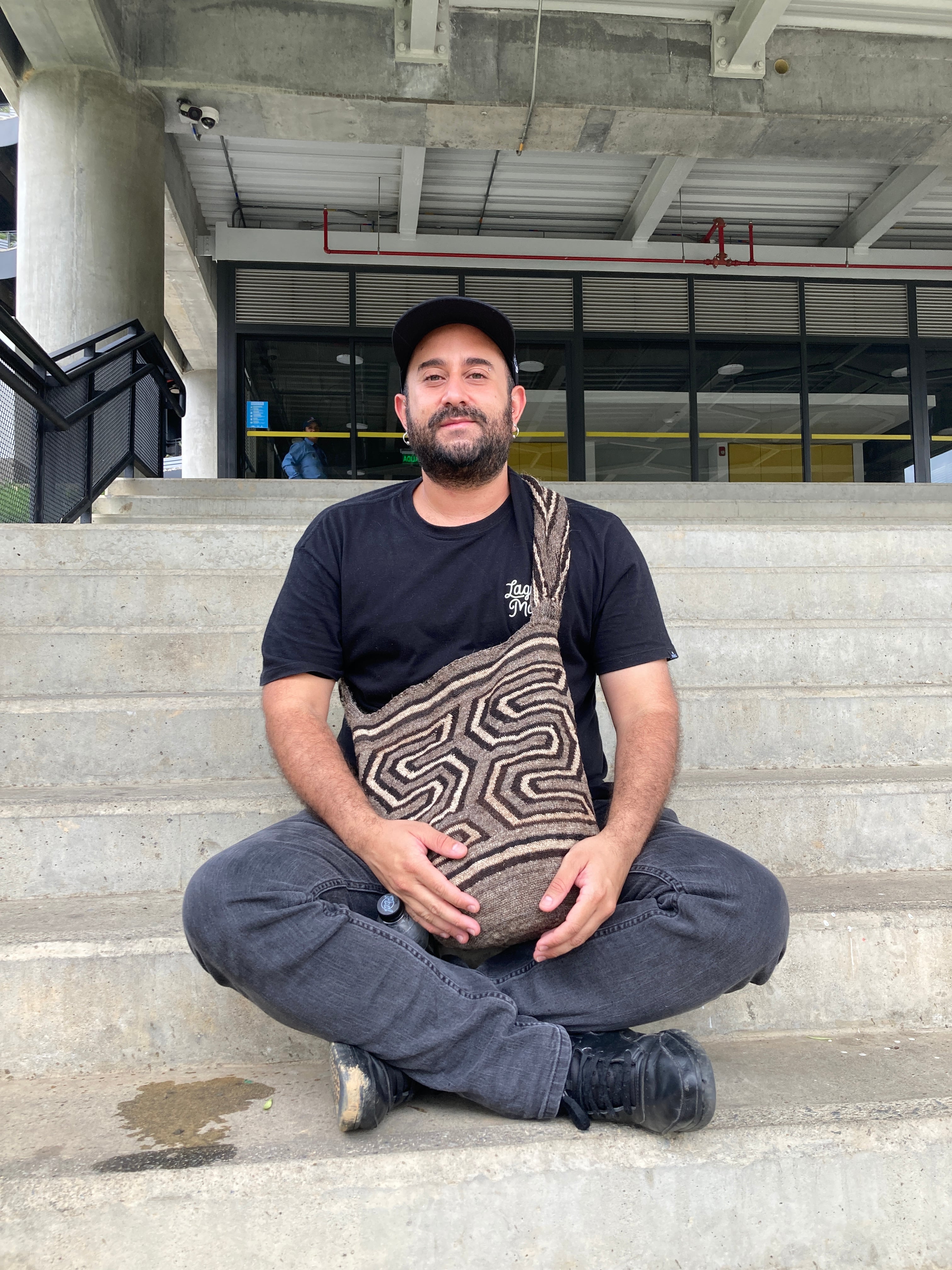 Luis Giraldo sentado en las escaleras de entrada a la Ciudadela de la Cuarta Revolución y la Transformación del Aprendizaje, iniciativa de la Alcaldía de Medellín en la Comuna 13