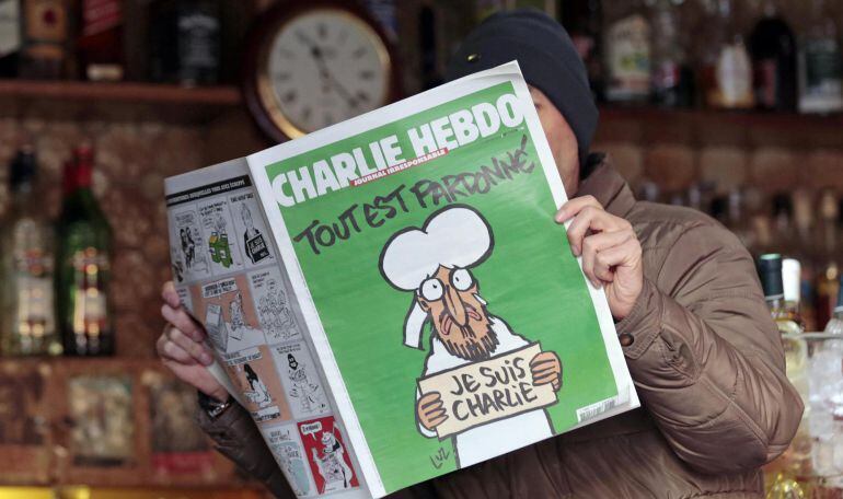 Un hombre lee un número de la revista Charlie Hebdo