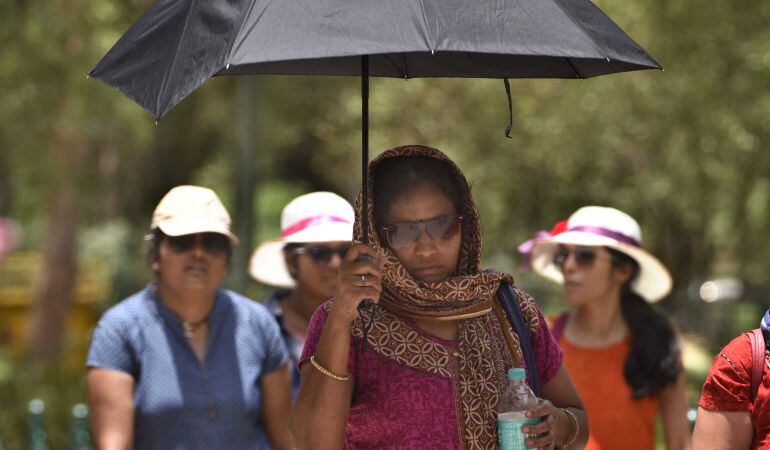 Mujeres paseando por Nueva Delhi (India) se protegen del sol y las altas temperaturas que rozaban los 48ºC en el mes de junio.