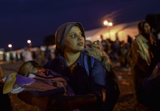 GEO36. Gevgelija (Macedonia, The Former Yugoslav Republic Of), 11/09/2015.- A migrant mother carrying her child waits for permission to leave registration camp and board the busses bound for Serbia, in Gevgelija, The Former Yugoslav Republic of Macedonia,