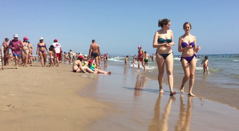 Decenas de veraneantes pasean en la playa de Gandía (Valencia).