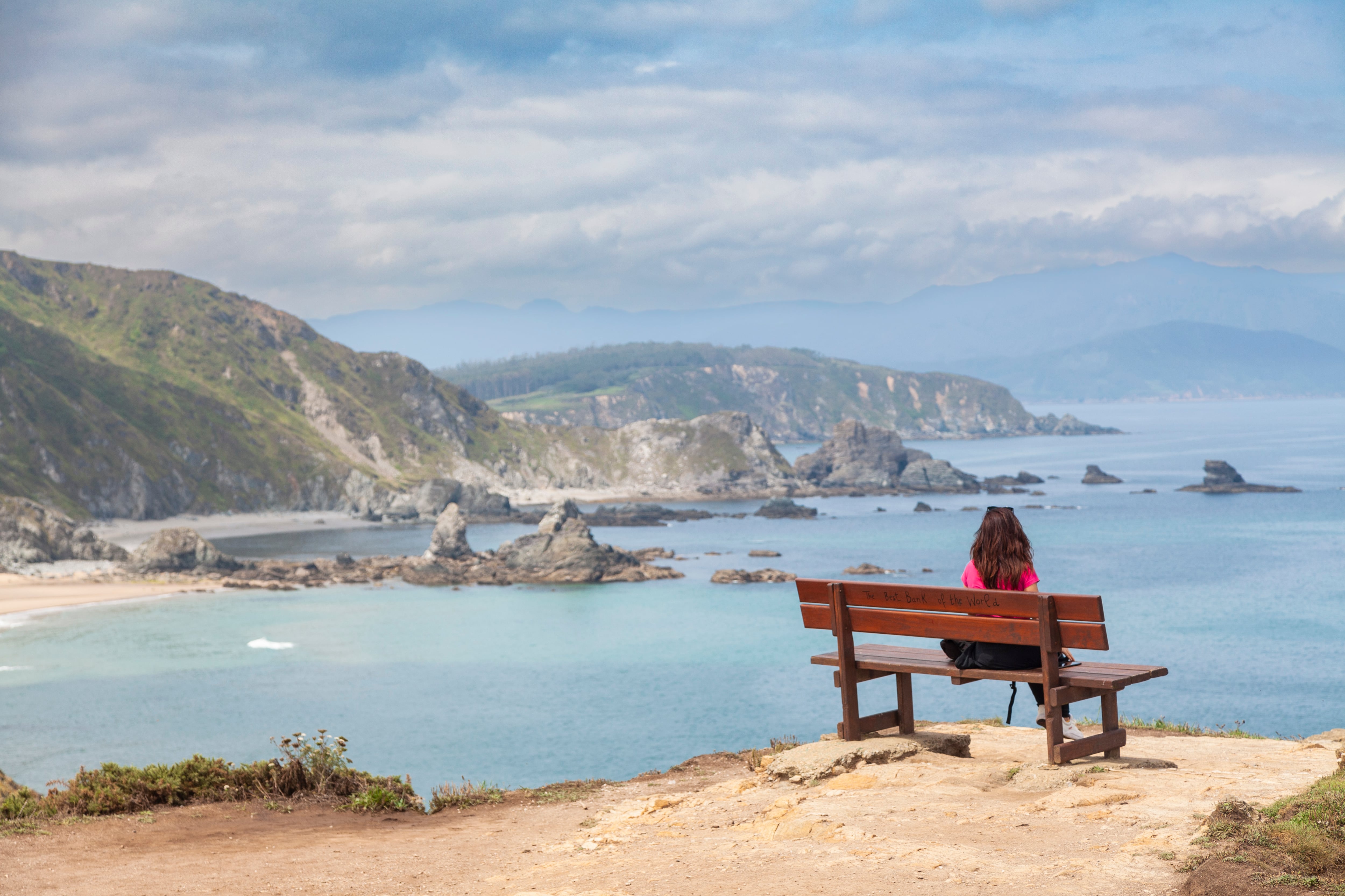 Ortigueira, Galicia, Spain. June 21, 2023, A woman contemplates the views, at the Mirador Do Coitelo, where the known as the &quot;Best bench in the world&quot;, the Banco de Loiba, is located. In summer there are usually queues to enjoy its views.