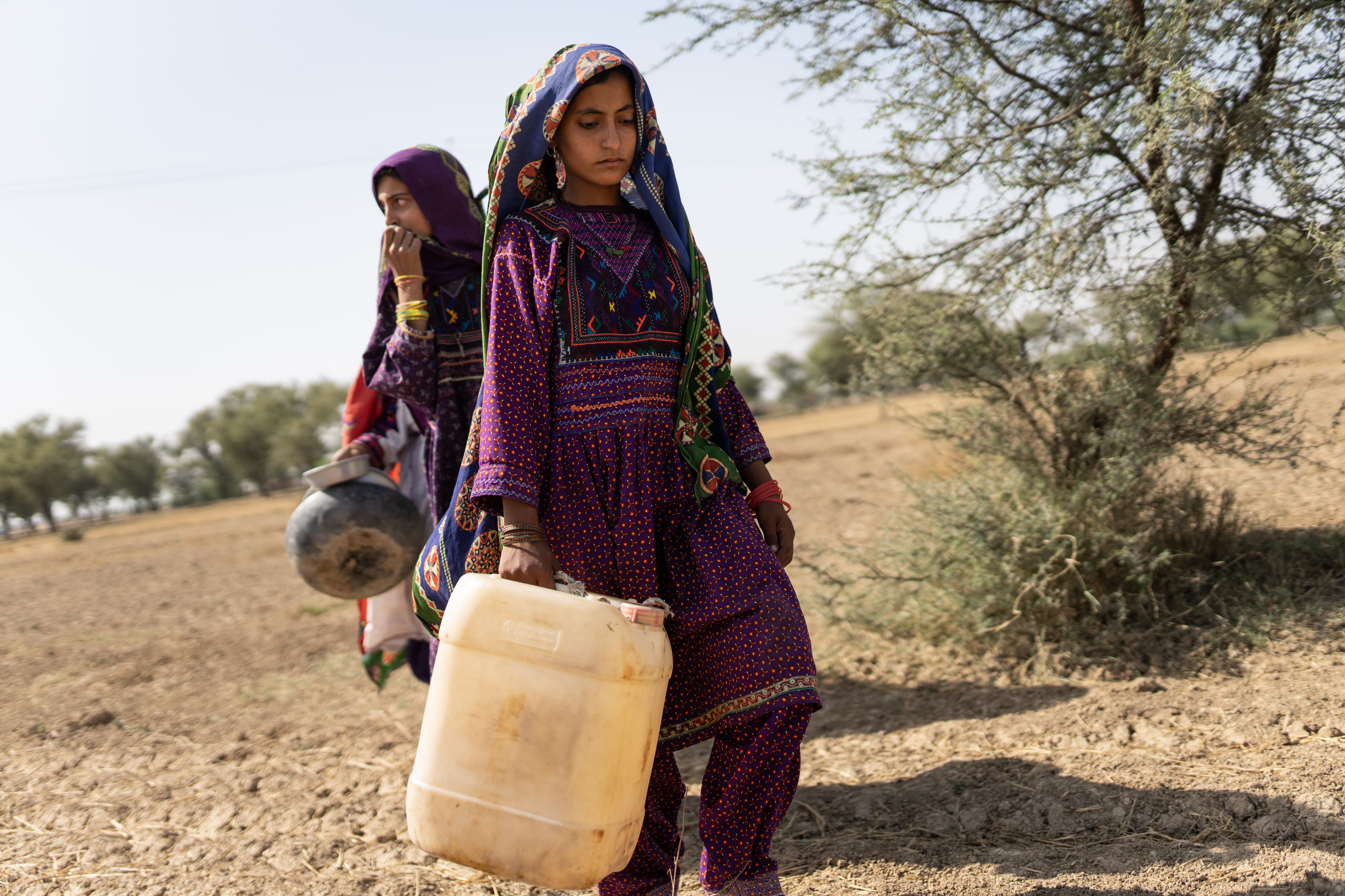 Saima, de 10 años, va a recoger agua junto a su hermana en Allah Abad, en Pakistán