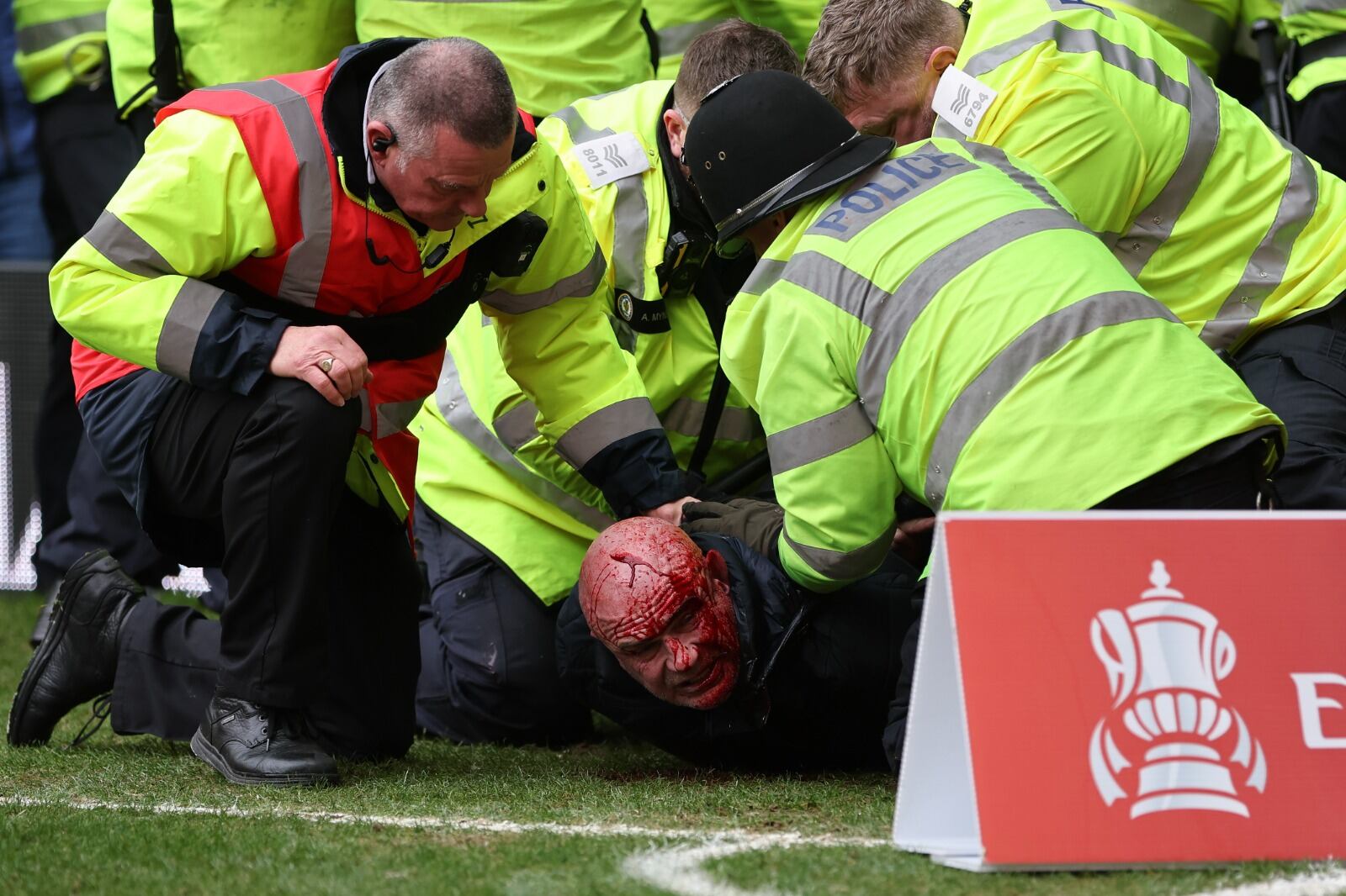 Un aficionado es interceptado en el césped después de los altercados entre los hinchas del West Bromwich Albion y  del Wolverhampton en la FA Cup