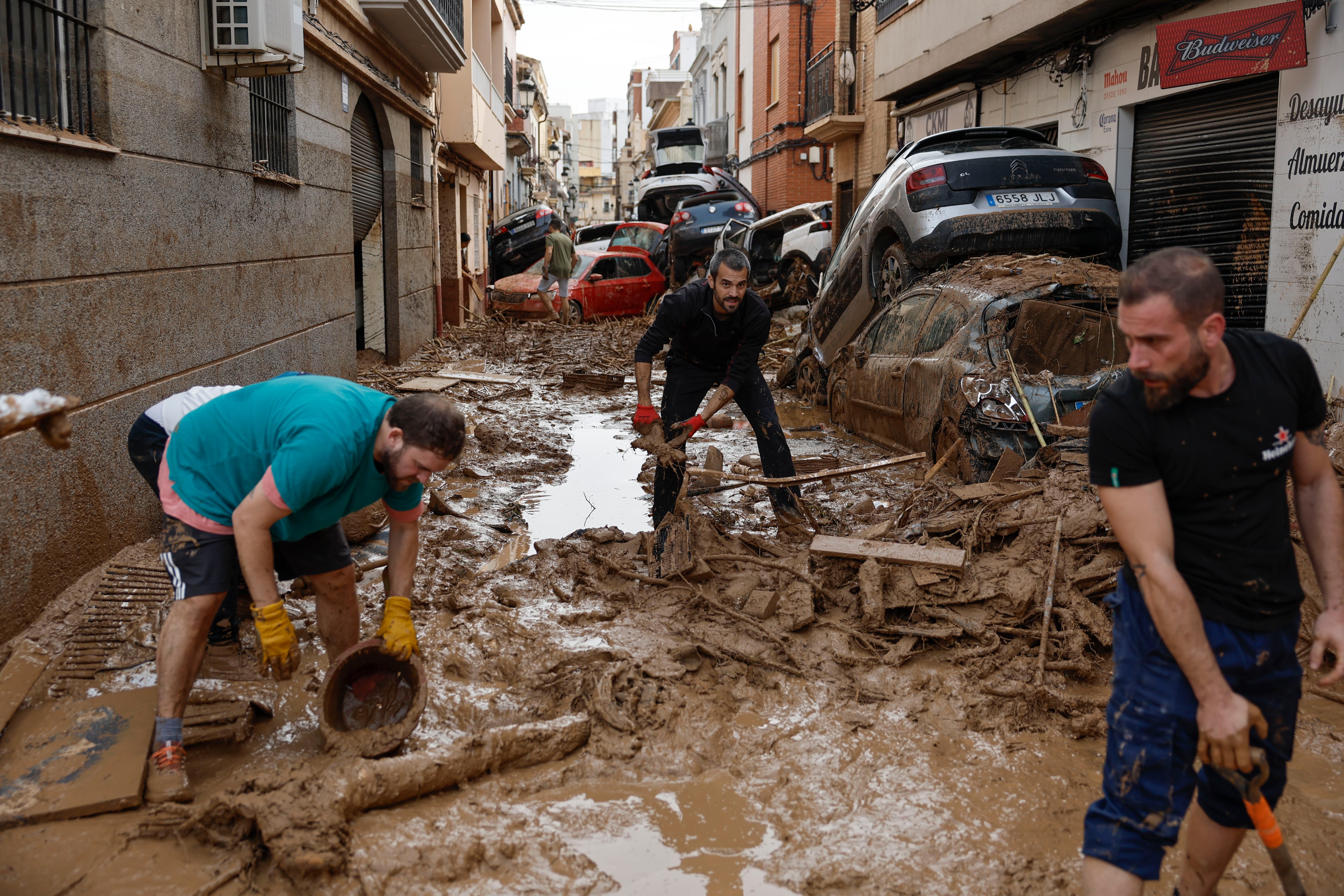 PAIPORTA, 01/11/2024.- Vecinos de Paiporta limpian el lodo de una calle afectada, este viernes. Las víctimas mortales en la provincia de Valencia a causa de la devastadora dana ha aumentado este viernes hasta las 202, según el último recuento facilitado por el Centro de Emergencias de la Generalitat Valenciana. EFE/Biel Aliño
