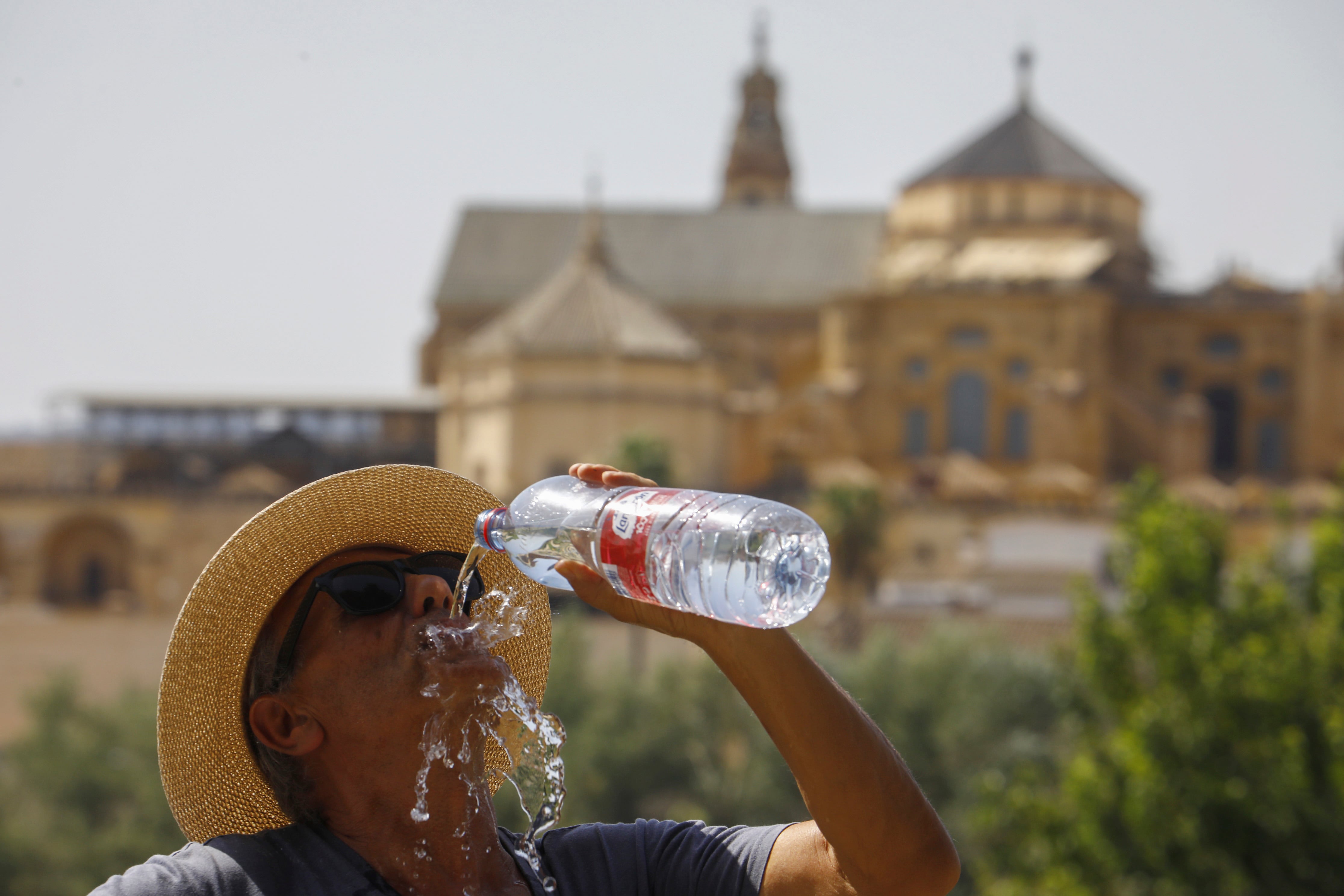 Un turista bebe agua ante la Mezquita-Catedral de Córdoba para combatir la ola de calor