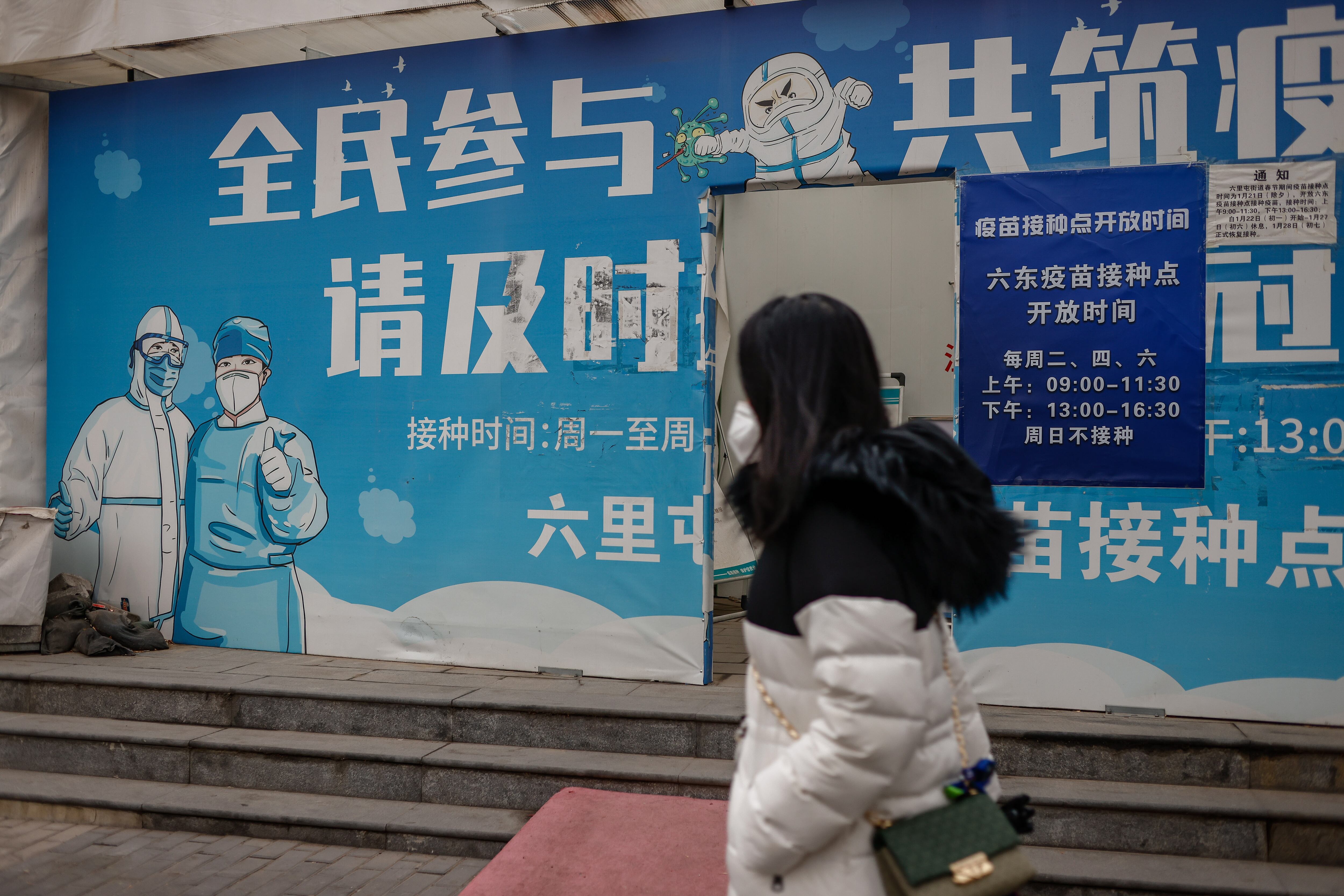 Una mujer camina frente a un centro de detección de COVID-19 en Beijing.