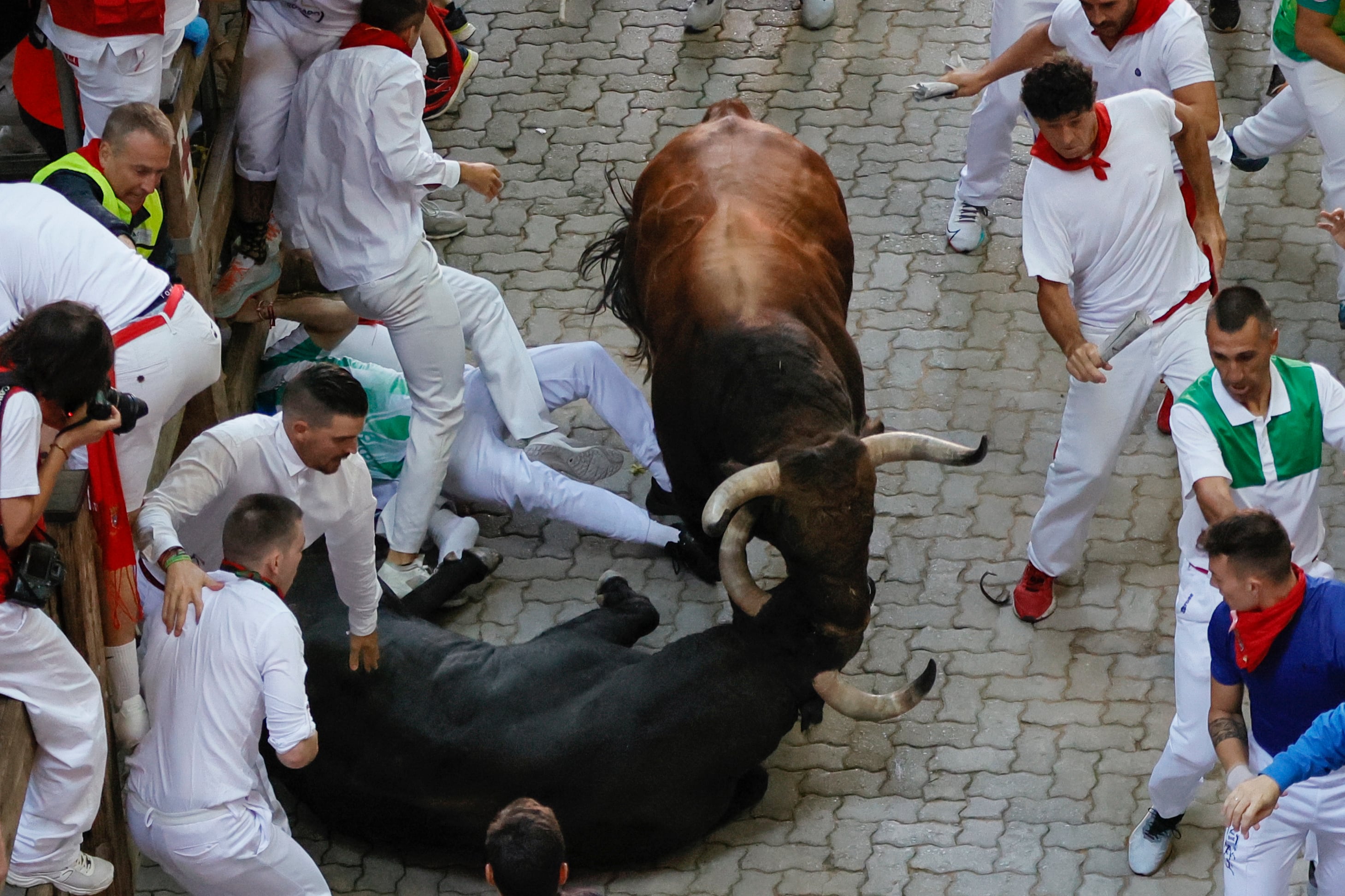 Un toro de la ganadería pacense de Jandilla cae a su llegada al callejón durante el sexto encierro de los Sanfermines que ha resultado una carrera rápida y emocionante