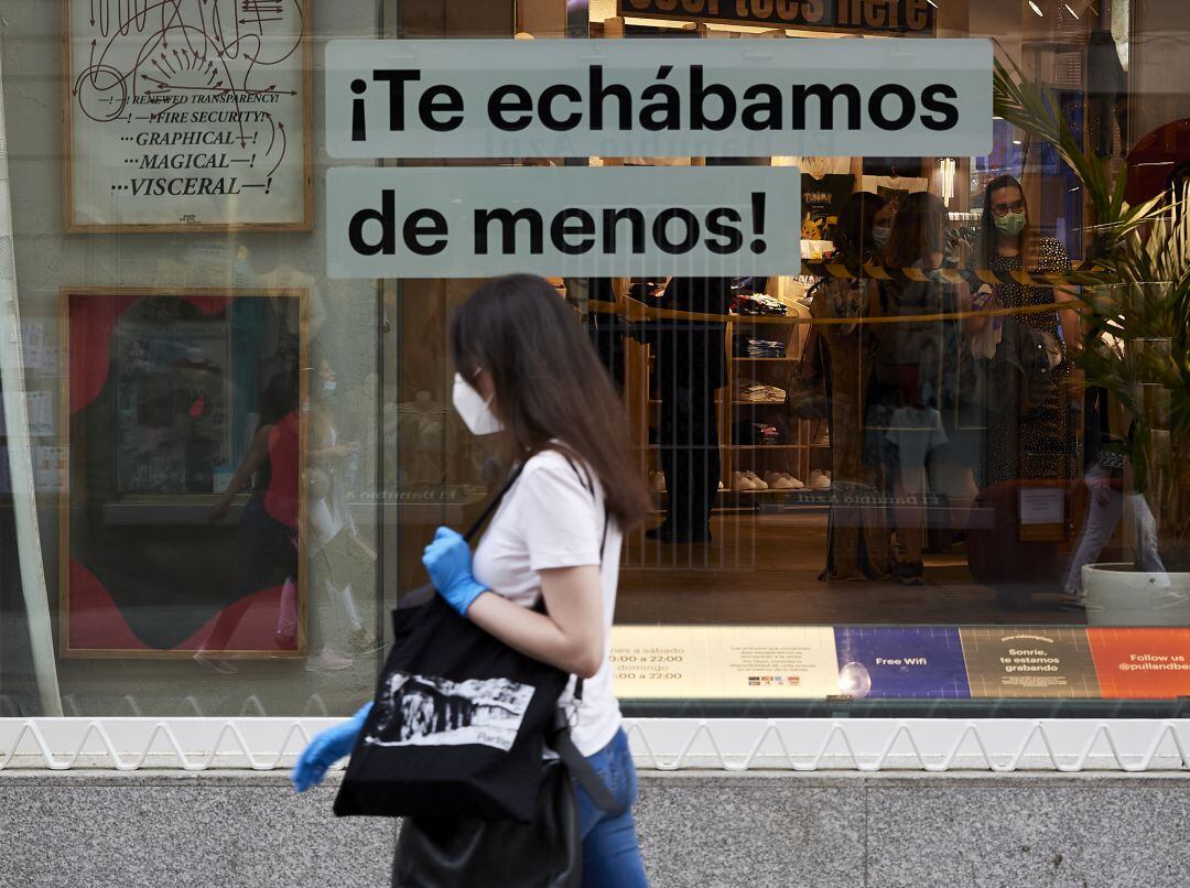 Una joven pasea delante de un escaparate en Madrid.