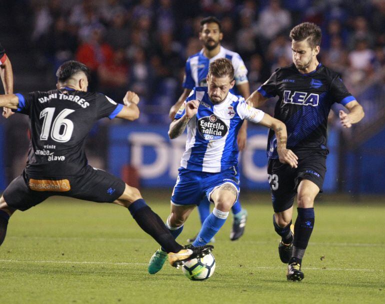 El delantero del Deportivo Fede Cartabia pelea un balón entre los jugadores del Alavés Álvaro Medrány Daniel Torres.