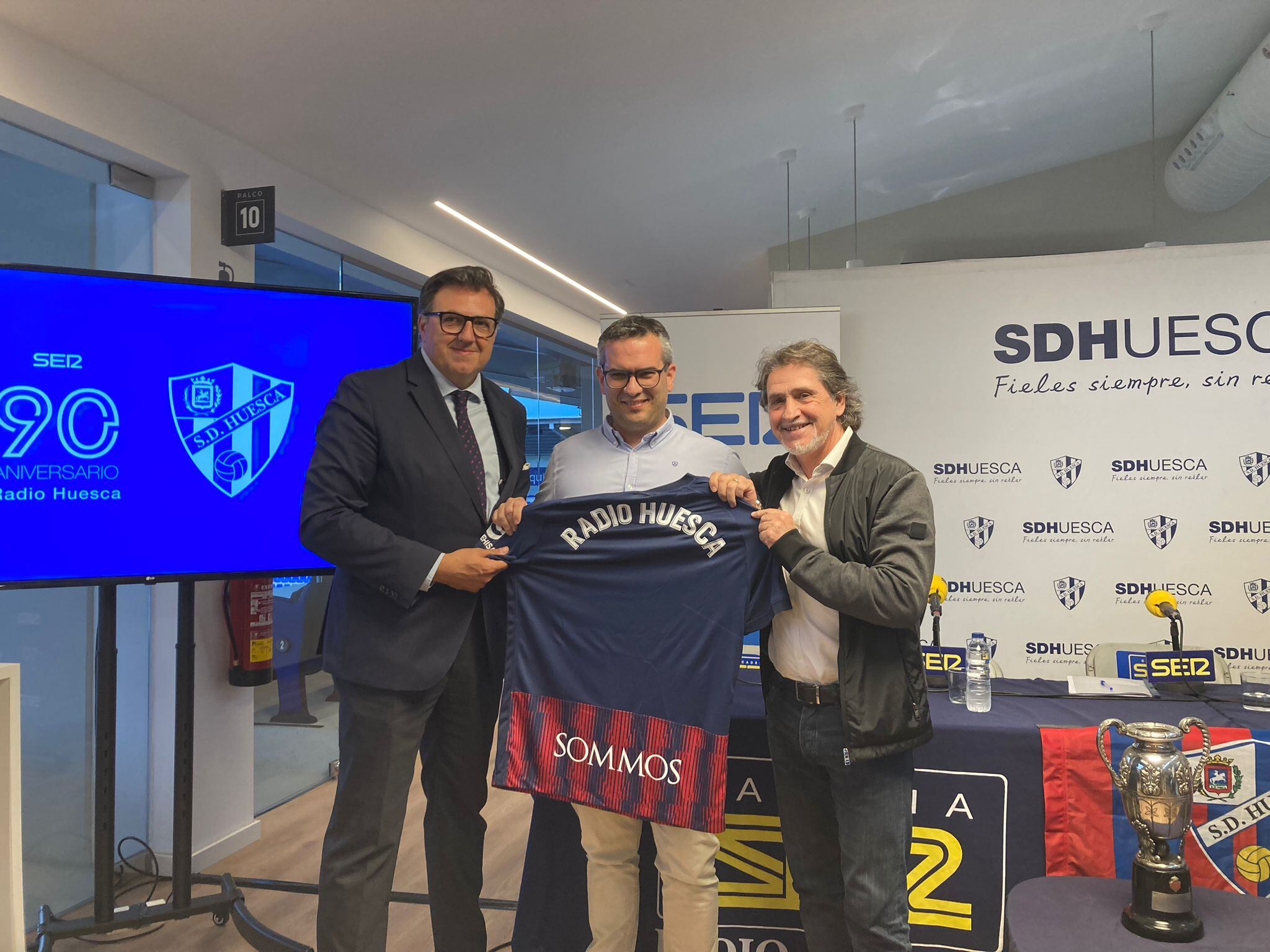 Fran Montaner recogió una camiseta con el nombre de Radio Huesca entregada por Manolo Torres y Raúl Ruiz