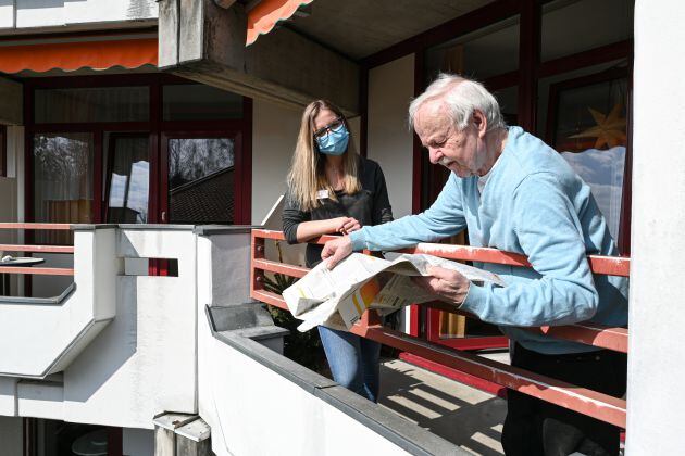 Anciano y cuidadora en el balcón de una vivienda