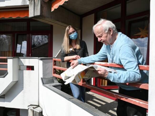 Anciano y cuidadora en el balcón de una vivienda