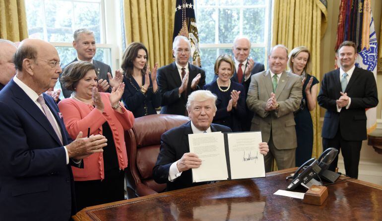 El presidente Donald Trump firma en el despacho oval el memorando sobre importación de aluminio.