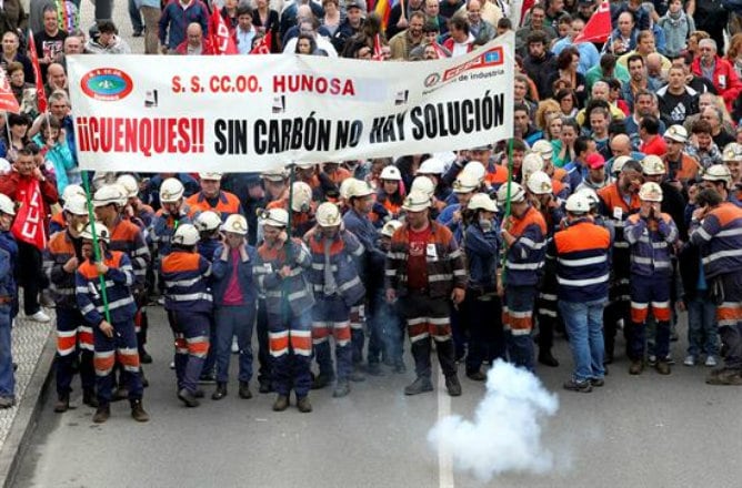 Varios mineros junto a cientos de personas durante la manifestación que ha tenido lugar hoy en Langreo (Asturias), con motivo de la huelga indefinida convocada por los sindicatos UGT y CCOO en protesta por los recortes previstospor el Gobierno central en 