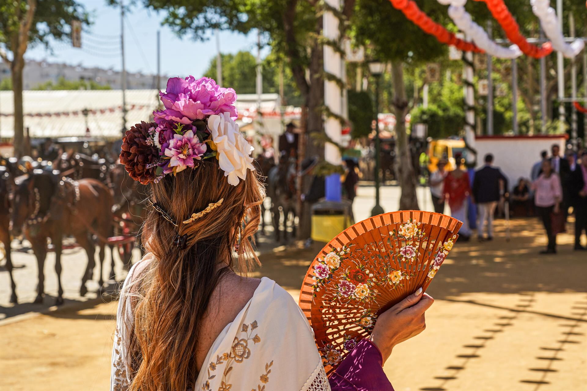 Archivo - Una mujer vestida de flamenca se abanica en el recinto ferial de la Feria de Abril de Sevilla, en foto de archivo. - Eduardo Briones - Europa Press - Archivo