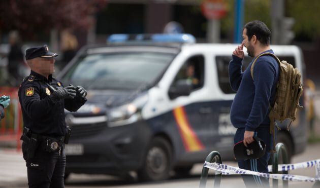 Un Policía Nacional habla con un transeúnte que caminaba por las inmediaciones del Palacio de Hielo de Madrid