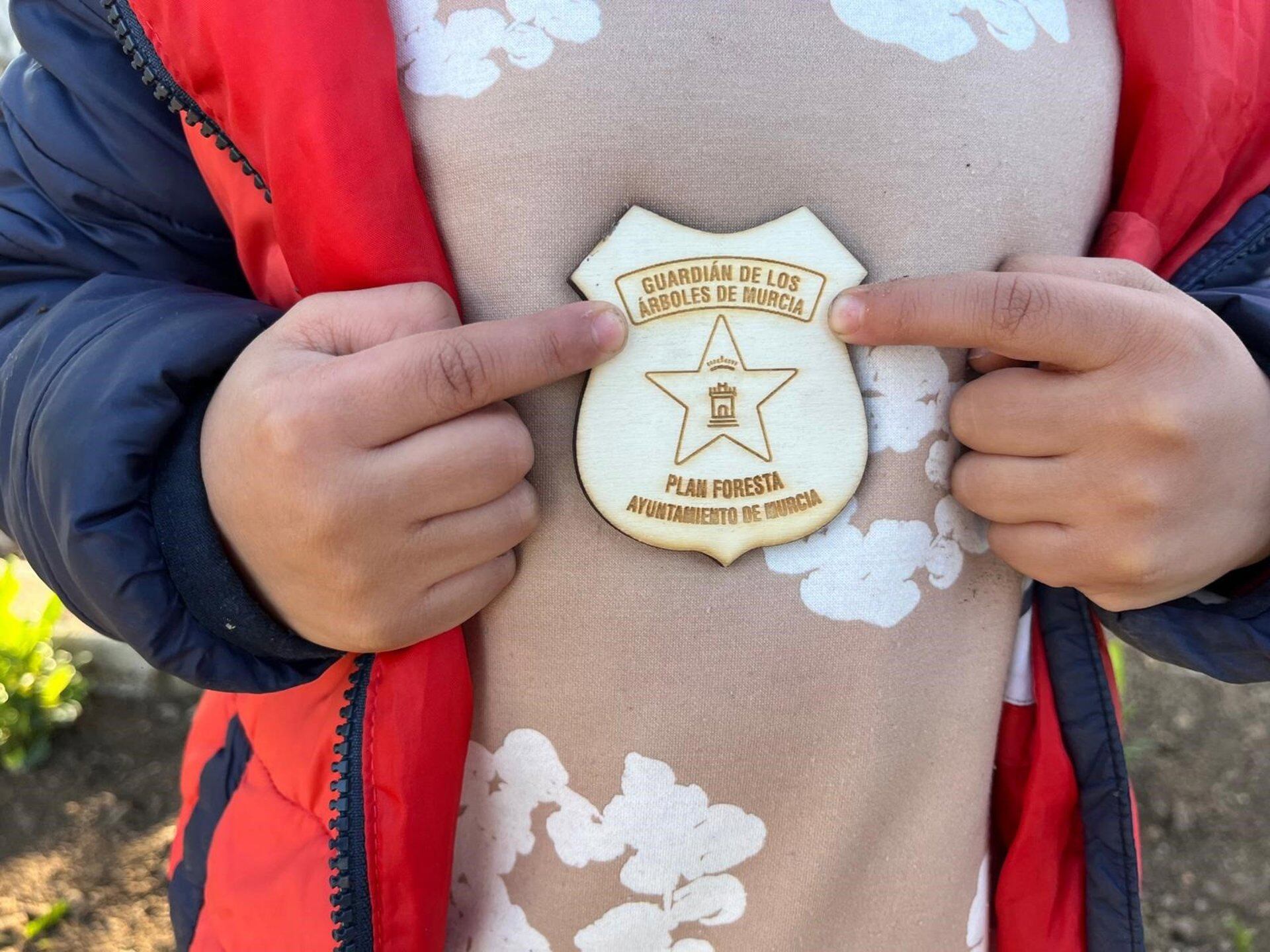 Un niño muestra un emblema de 'Guardián de los árboles de Murcia'