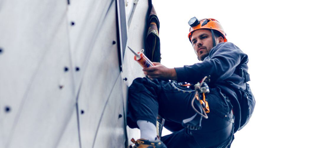 Trabajador colgado en la parte exterior de un edificio