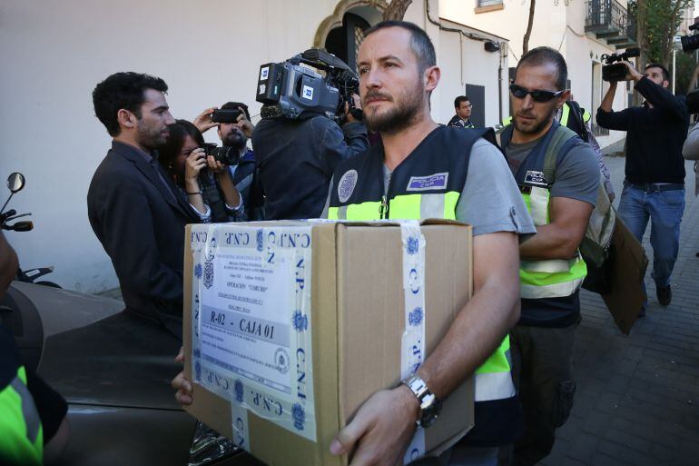 Miembros de la policia nacional salen de la viviende de Oleguer Pujol con cajas tras unas 8 horas de registro. Barcelona, 23 de noviembre de 2014 [Albert Garcia]