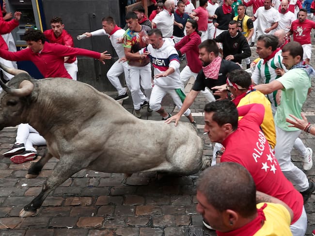 Mozos corren junto a uno de los toros de la ganadería abulense de José Escolar Gil durante el séptimo encierro de los Sanfermines 2024