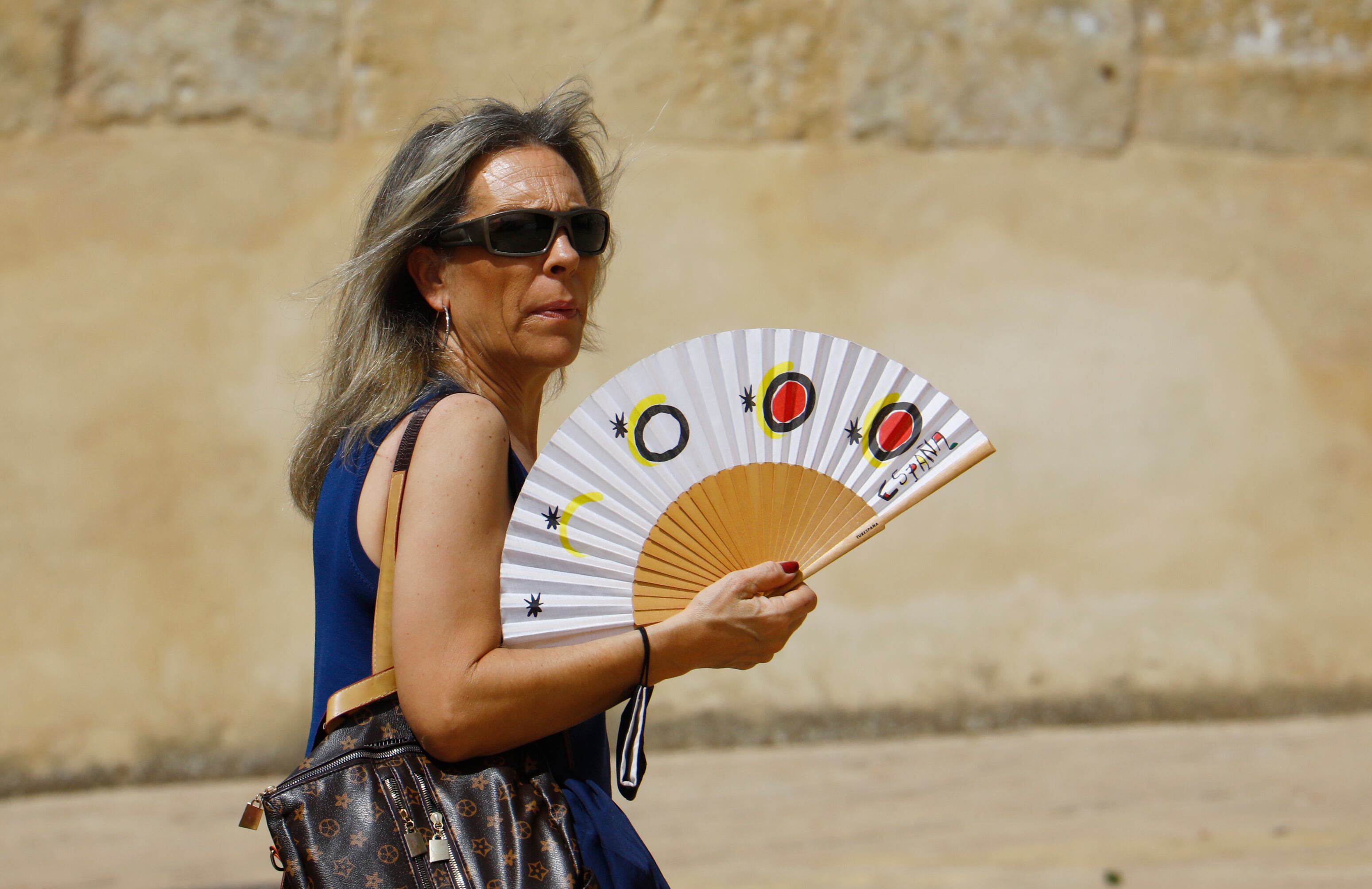 Una turista se abanica para aliviar el calor en Córdoba.