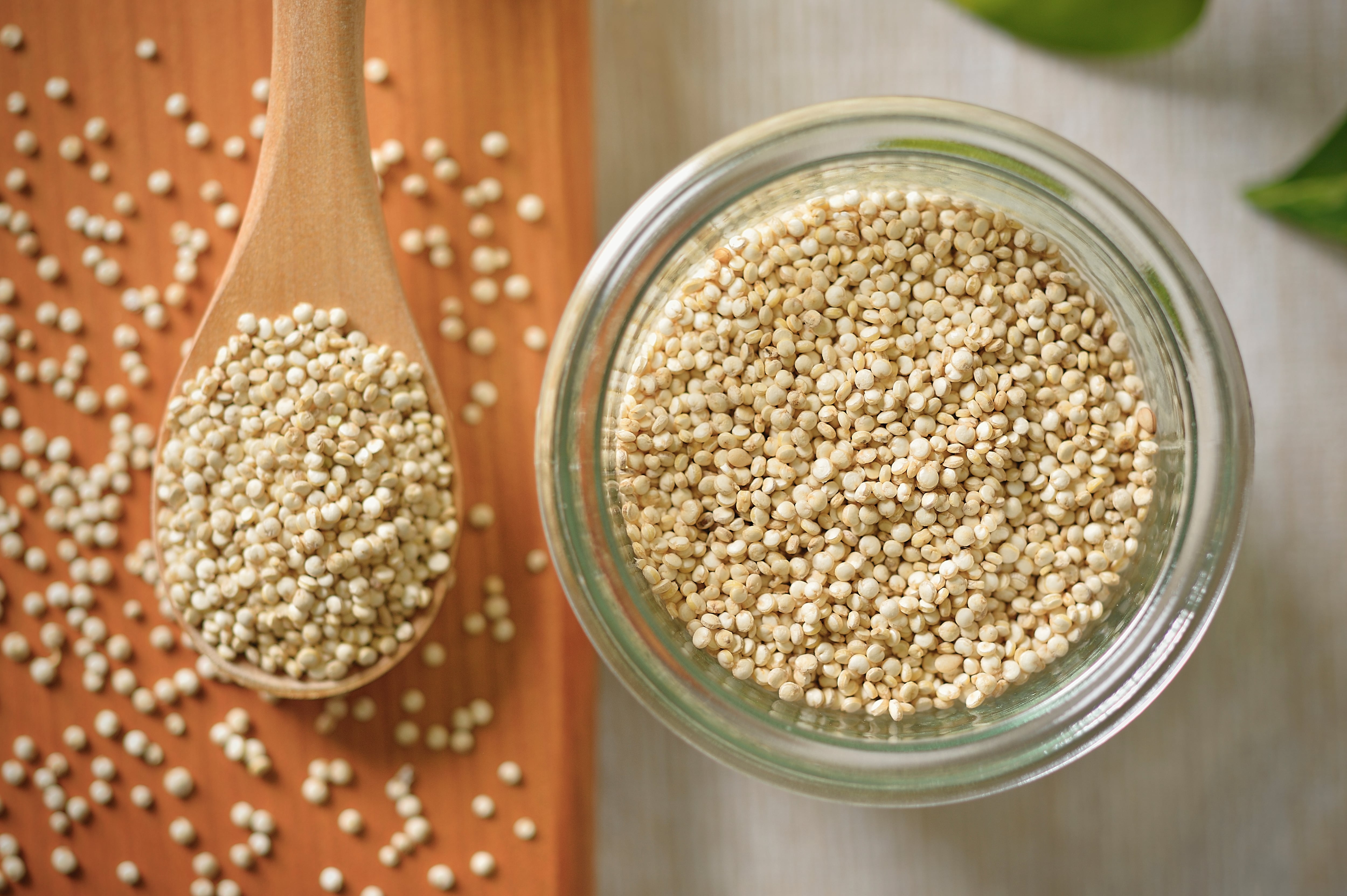 Quinoa is in the glass container and a wooden spoon,Super food