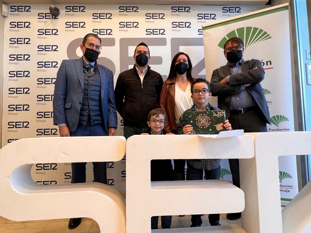 Gustavo Ruiz Montiel ganador del &quot;Abrazo Sonoro 2021&quot; junto a su hermano Raúl. Tras ellos el director de la Fundación Unicaja, Sergio Corral, los padres de los niños, Soledad y Gustavo, así como el director de la Cadena SER Málaga, José Manuel Atencia.