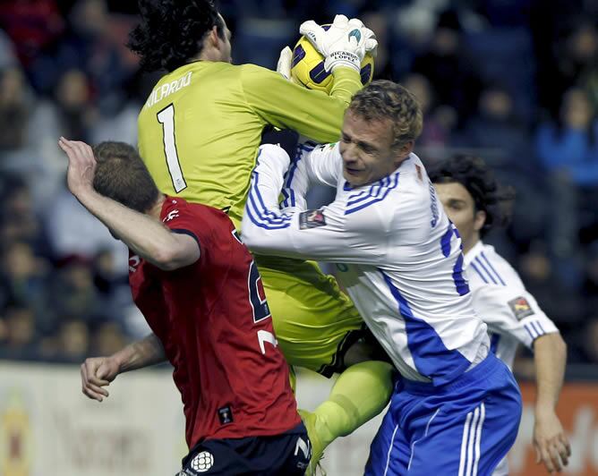 El guardameta del Osasuna Ricardo López atrapa el balón bajo la defensa de su compañero Sergio Fernández y ante el defensa checo del Real Zaragoza Jiri Jarosik