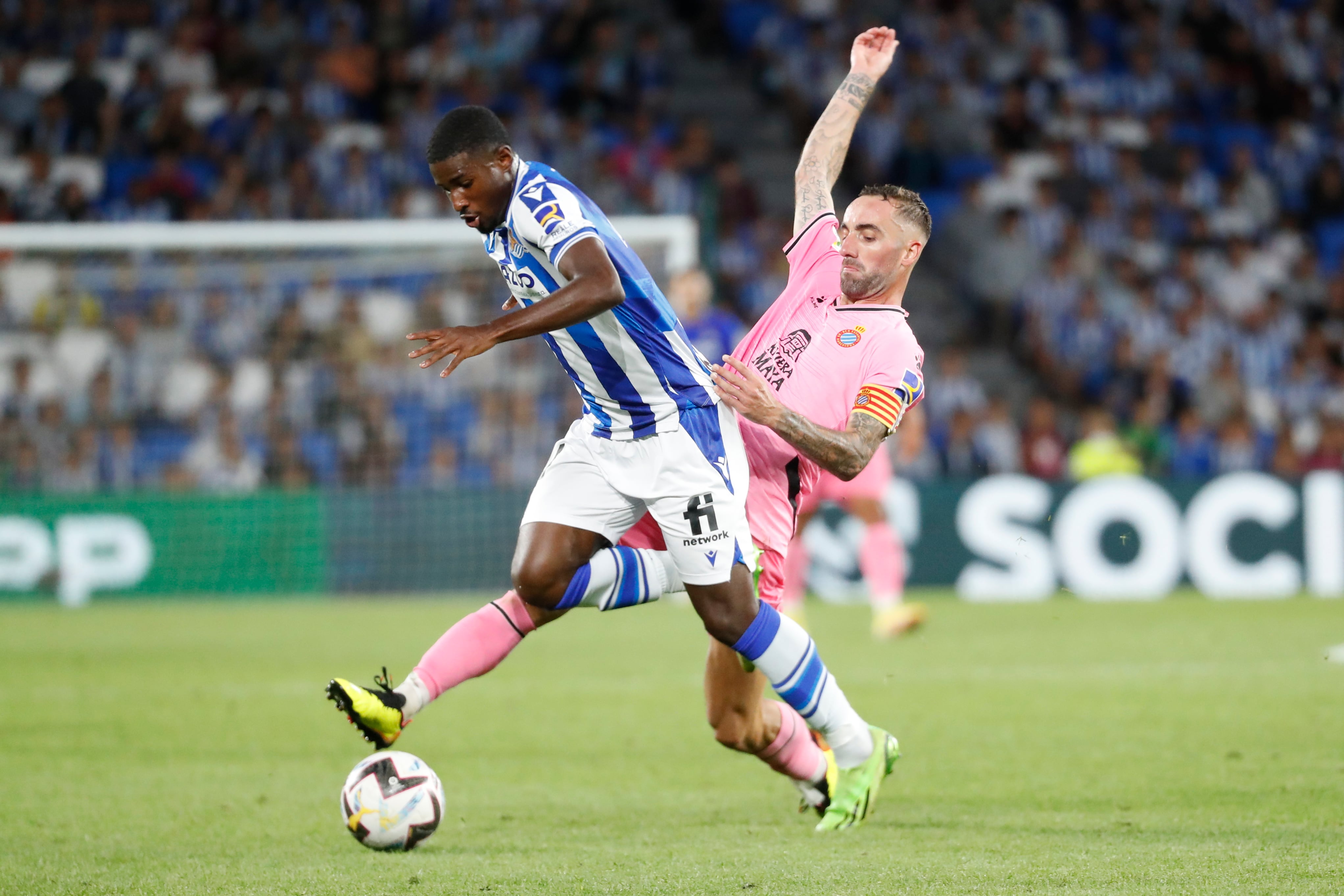 SAN SEBASTIÁN, 18/09/2022.- El centrocampista inglés de la Real Sociedad, Mohamed Ali-Cho (i), intenta llevarse el balón ante el centrocampista del Espanyol, Sergi Darder, durante el encuentro correspondiente a la sexta jornada de primera división que disputan hoy domingo en el estadio de Anoeta, en San Sebastián. EFE / Juan Herrero.