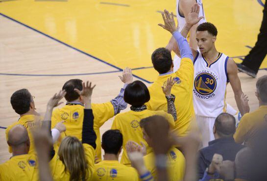 Stephen Curry choca la mano con algunos aficionados que acudieron a l Oracle Arena de Oakland