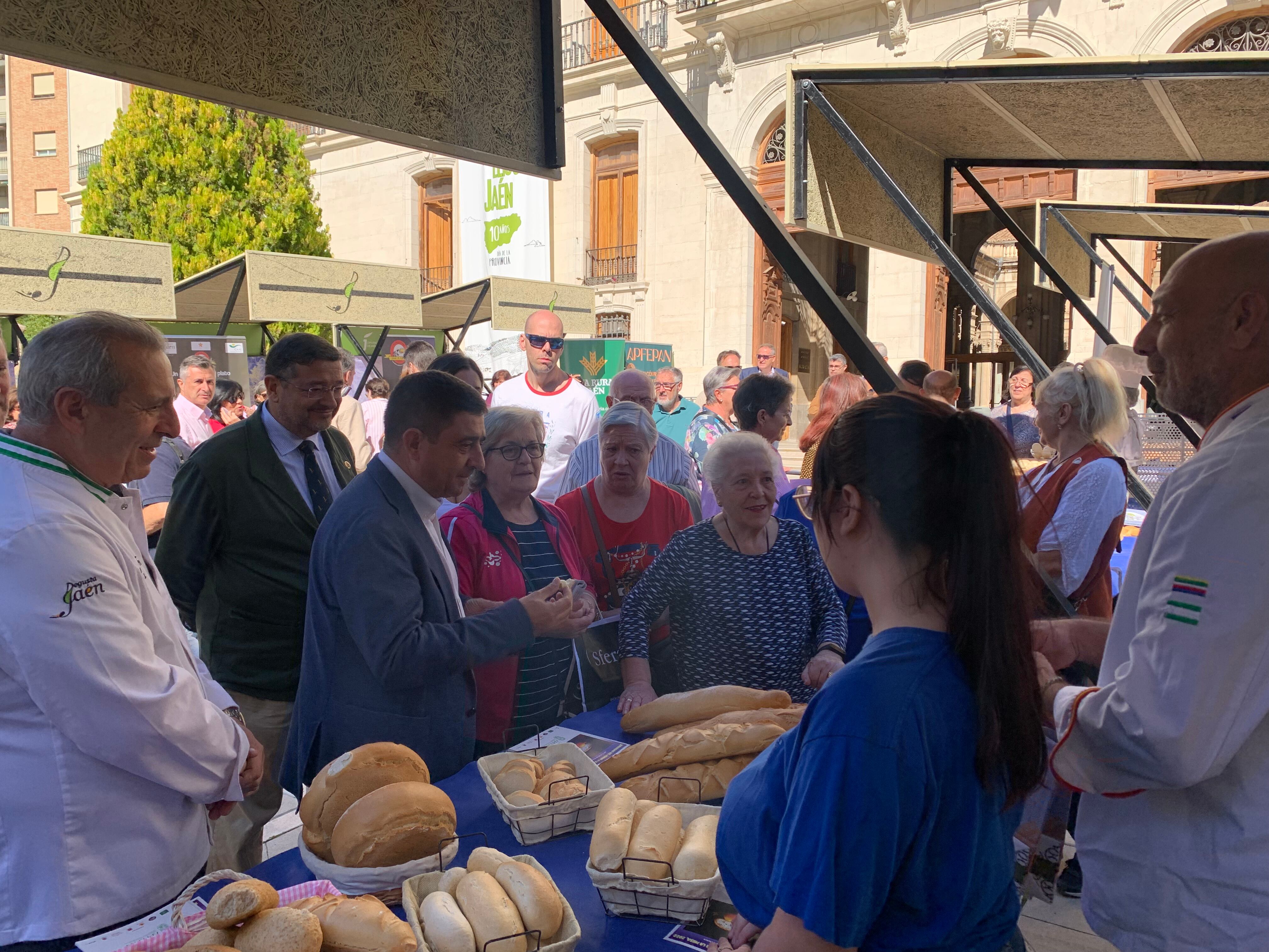 El presidente de la asociación de panaderos, Juan Antonio García, y el presidente de la Diputación, Francisco Reyes, frente a uno de los puestos de pan instalados en la lonja.