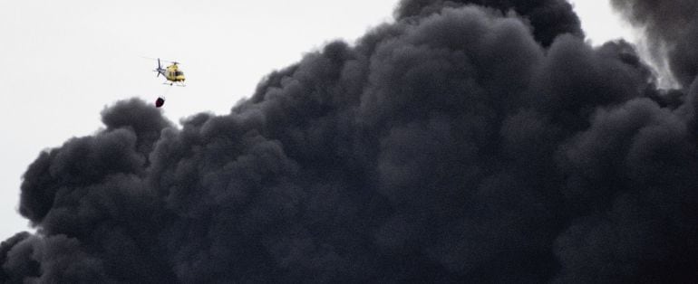 Un helicóptero de los servicios de emergencias trabajan en la extinción del incendio producido en el cementerio de neumáticos de Seseña (Toledo)