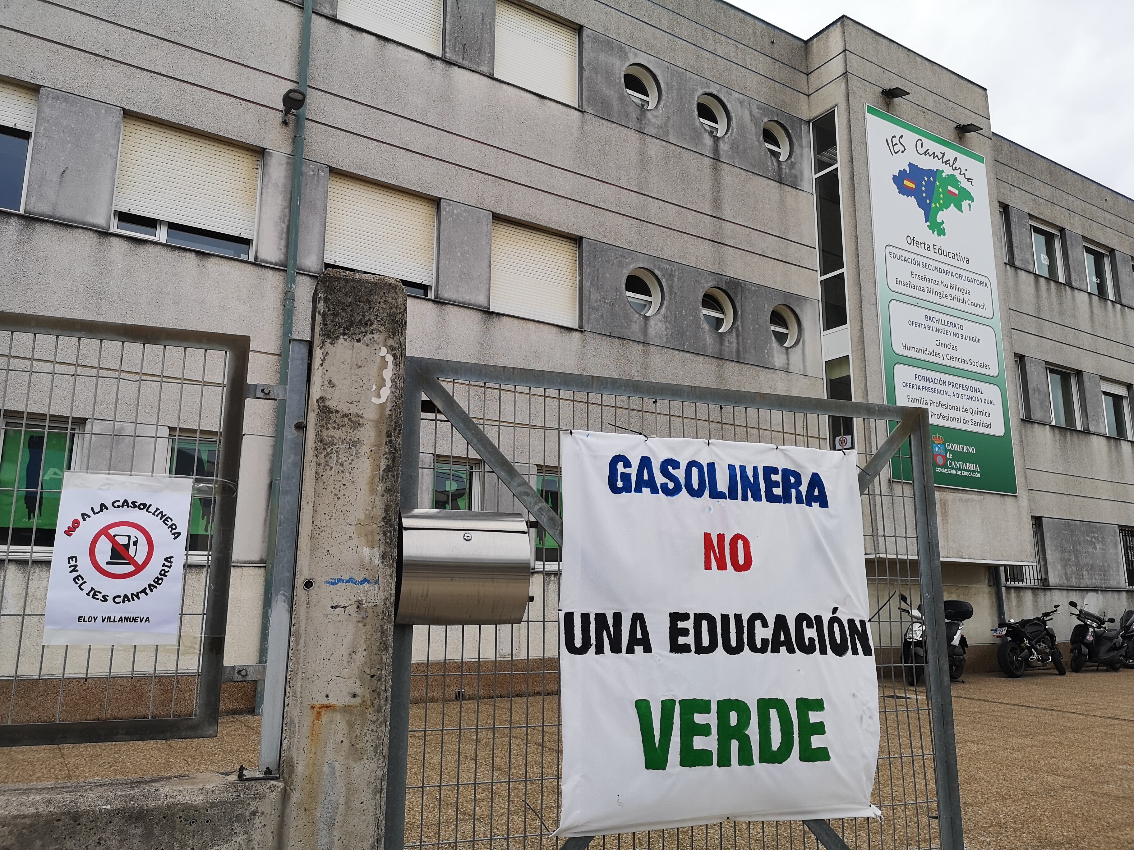 Carteles en la valla del IES Cantabria rechazando la construcción de una gasolinera junto al centro educativo.