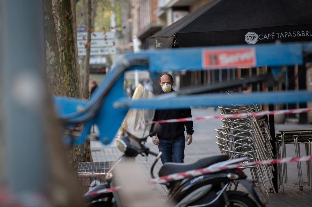Un home protegit amb una mascareta camina a prop d'una obra