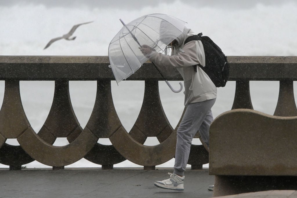 Una persona se protege de la lluvia y el viento en A Coruña.