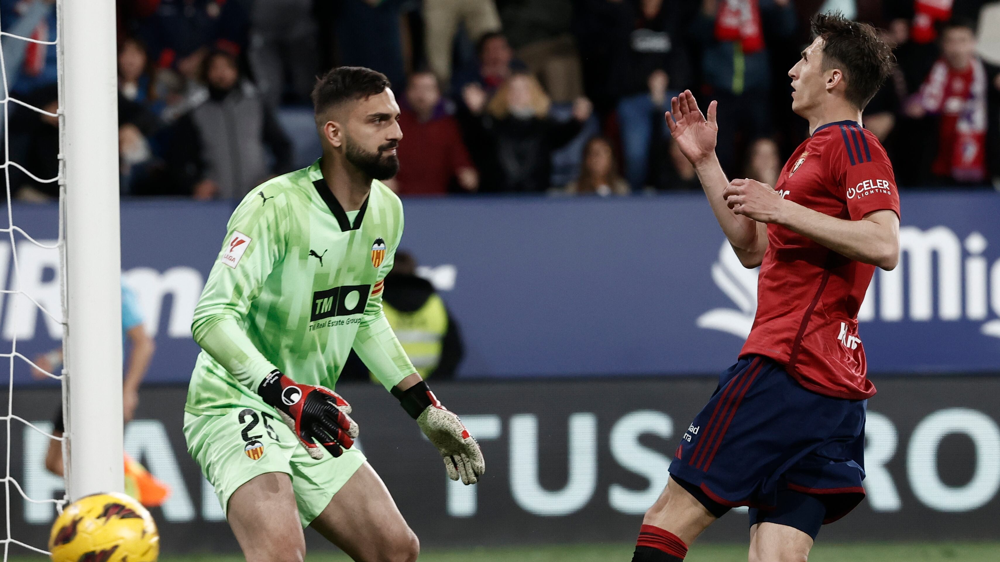 PAMPLONA, 15/04/2024.- El delantero de Osasuna Ante Budimir (d) ante el portero Giorgi Mamardashvili, del Valencia, durante el partido de LaLiga en Primera División que CA Osasuna y Valencia CF disputan este lunes en el estadio de El Sadar, en Pamplona. EFE/Jesús Diges
