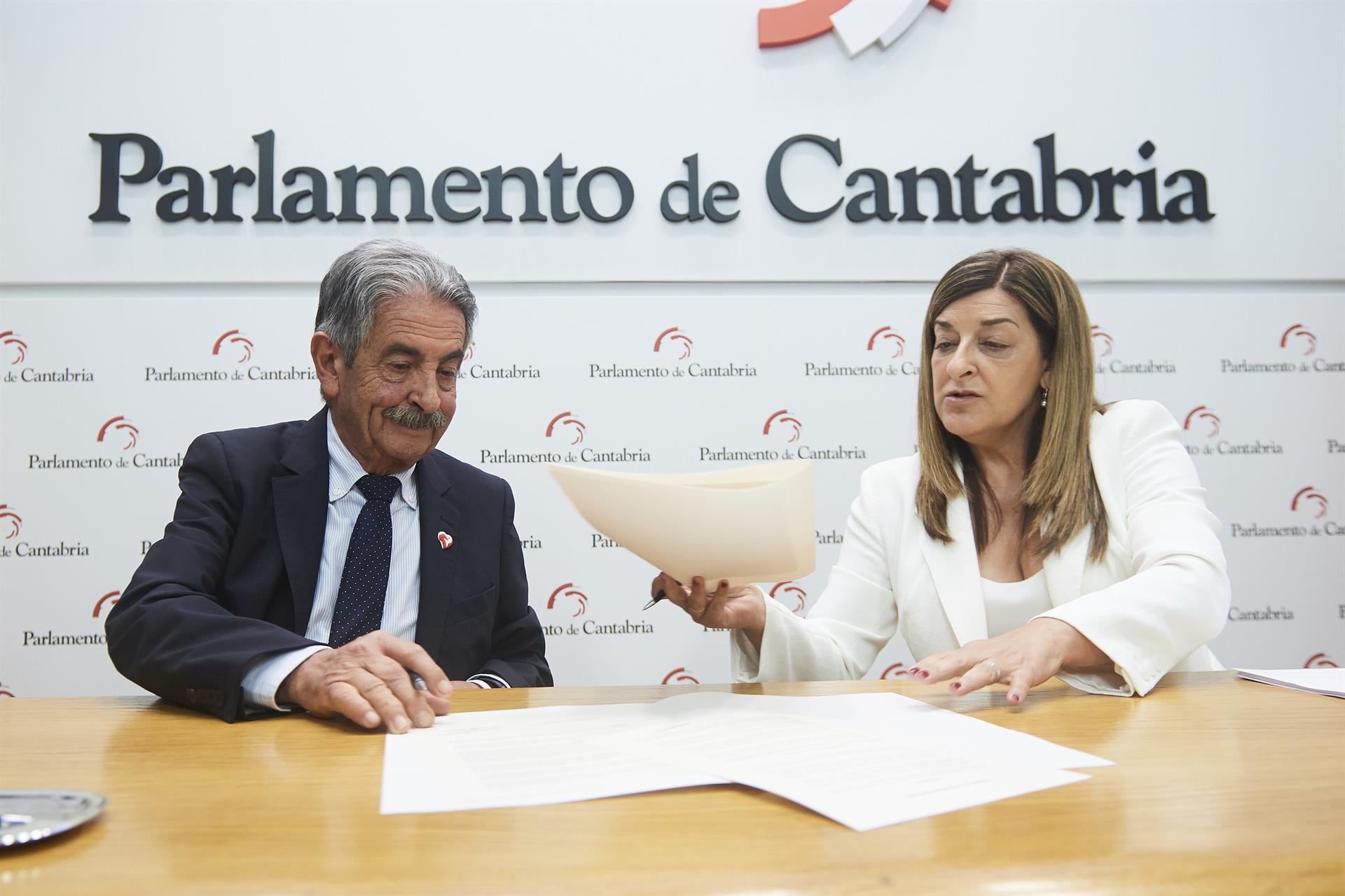 La presidenta del Partido Popular de Cantabria, María José Sáenz de Buruaga, firma con el secretario general del PRC, Miguel Ángel Revilla, el acuerdo para su investidura. - César Ortiz - Europa Press