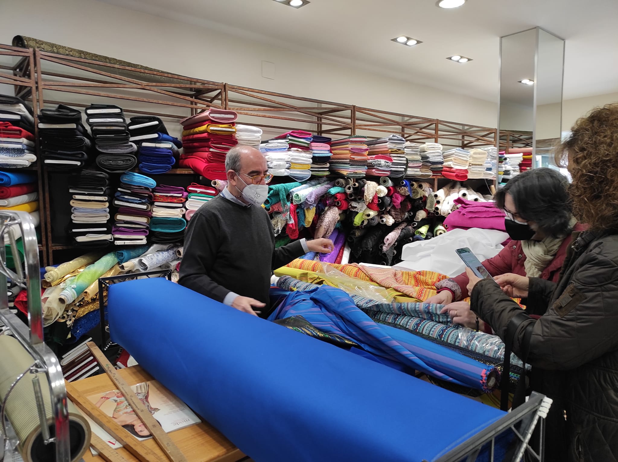 Julián atiende a dos mujeres en su comercio de telas