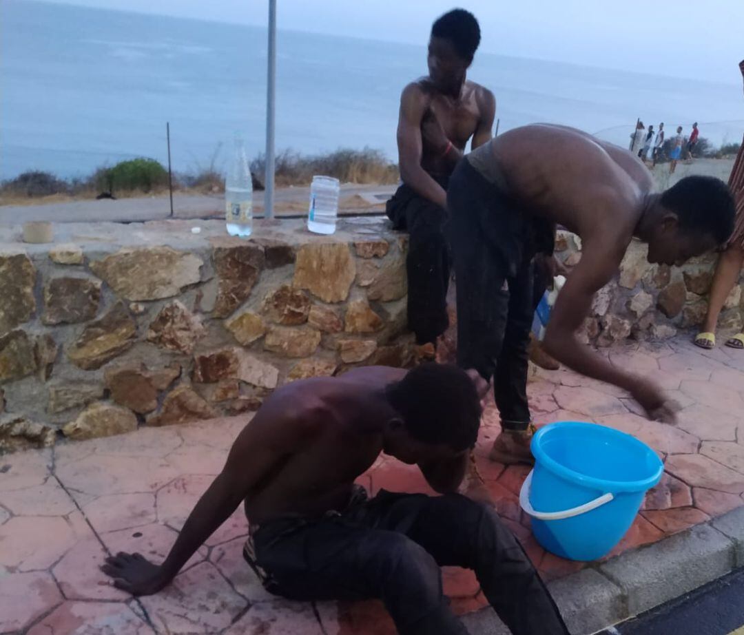 Los migrantes, lavándose con agua las heridas de las concertinas