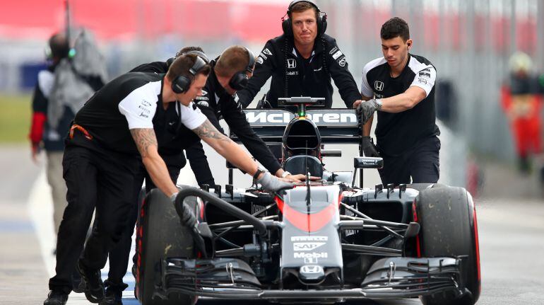 Algunos mecánicos tiran del coche de Fernando Alonso