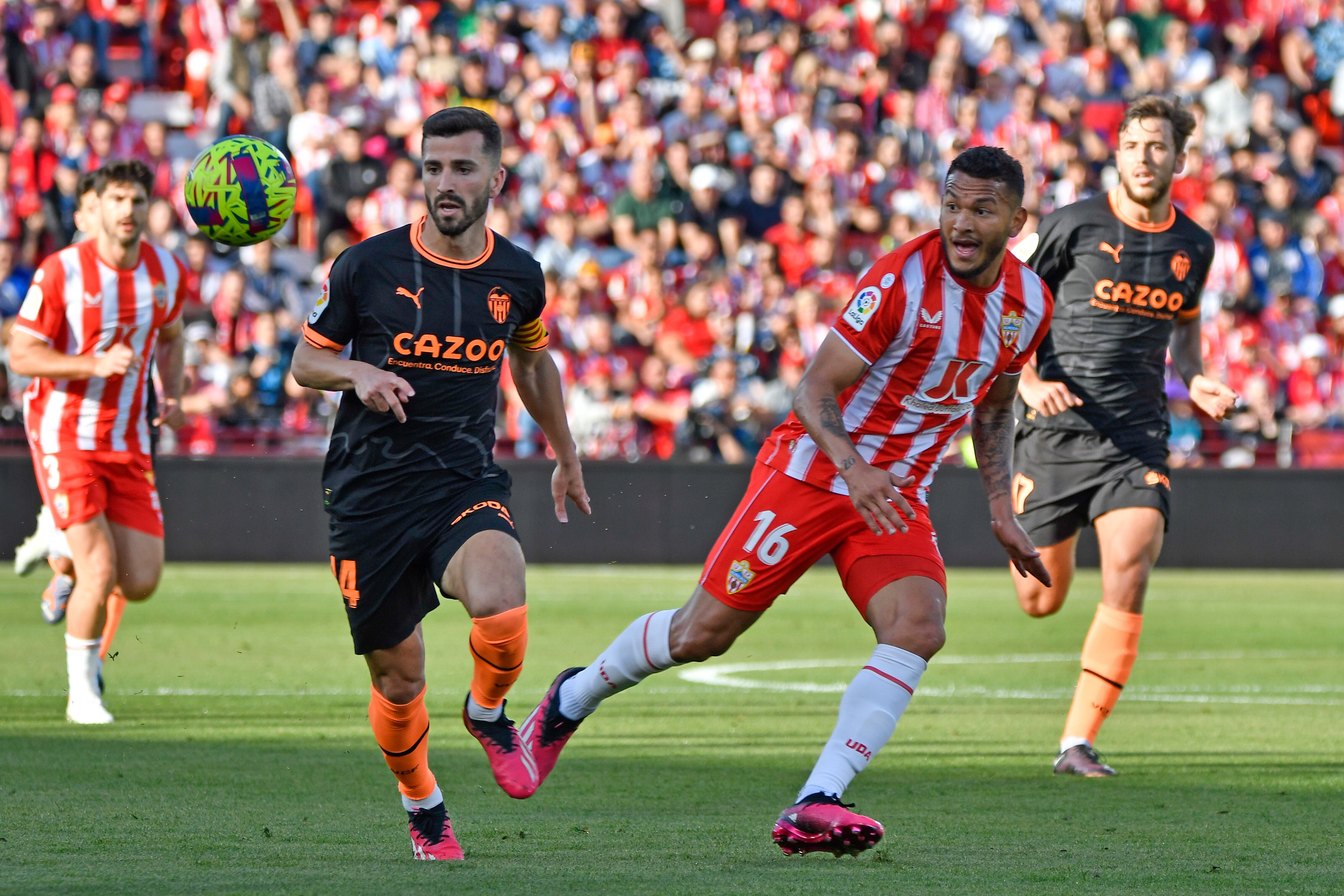 El delantero colombiano de la UD Almería Luis Suárez (d) disputa un balón con el defensa del Valencia C.F. Gayá (ci), durante el partido celebrado este domingo en Power Horse Stadium de Almería durante la jornada 28 de LaLiga Santander. EFE / Carlos Barba