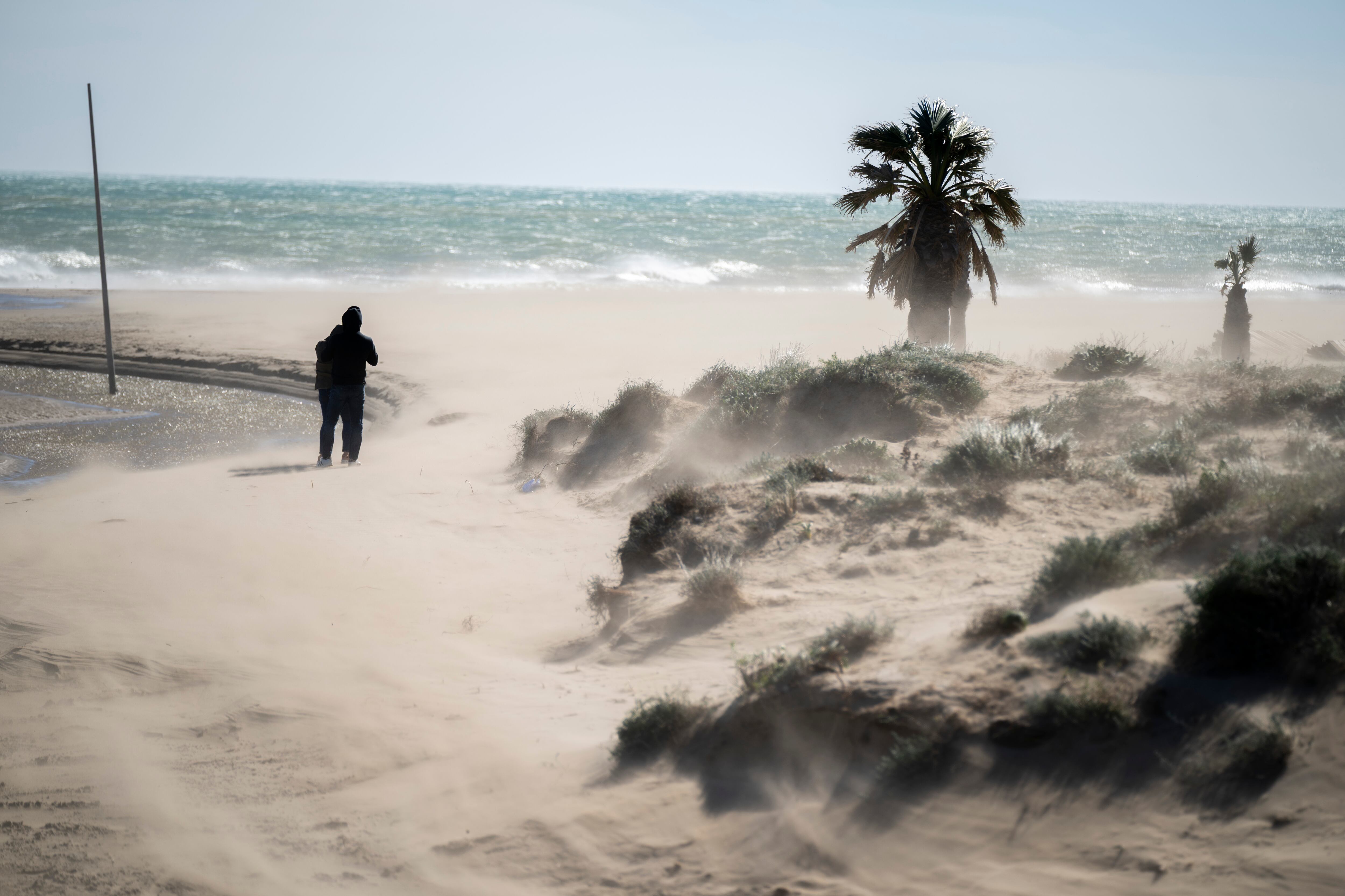 Varias personas pasean por la playa del Gurugú durante una jornada de viento este sábado en Castellón.